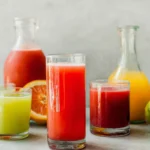 Colorful glasses and pitchers of fresh fruit drinks including watermelon and lime flavors, representing a classic agua fresca recipe.