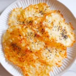 A plate of crispy, golden-brown chips topped with black sesame seeds, made using the cottage cheese chips recipe.
