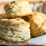 Flaky golden biscuits stacked in a basket made using a 3 ingredient biscuit recipe with self-rising flour, butter, and yogurt.
