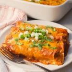 Plate of freshly baked enchiladas topped with melted cheese, chopped onions, and cilantro from a cheese enchilada recipe.
