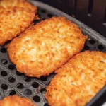 Golden crispy hash browns in air fryer basket during cooking