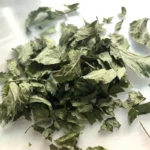Close-up of dried lemon balm leaves on a white surface after air drying