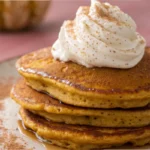 pumpkin pancakes on a plate with syrup and cream