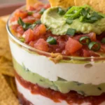 7 layer dip with avocado and tomato, nachos on plate