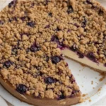 A warm blueberry crumble with a golden topping served in a baking dish, showcasing a classic American dessert.