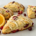 Freshly baked cranberry orange scones with a golden crust served as a breakfast sweet.