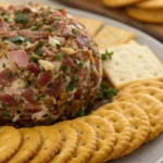 dried beef cheeseball coated with chopped meat and herbs served with crackers on a platter.