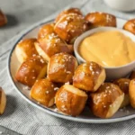 Freshly baked pretzel bites with a golden brown crust served warm ON PLATE WITH SAUCE DIP