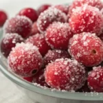 Fresh cranberries coated in sparkling sugar creating frosted candied cranberries for desserts and garnishes.