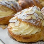 Almond croissants with flaky layers and a rich almond filling topped with sliced almonds and powdered sugar.