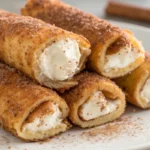French toast roll ups cooked until golden and filled with sweet cream cheese shown as bite sized breakfast roll ups.