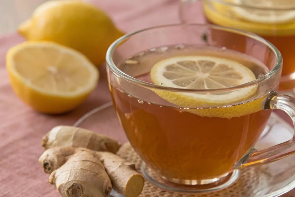 Lemon ginger tea served warm in a clear cup with fresh lemon slices and ginger creating a calm healthy drink aesthetic.