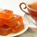 bariatric gelatin recipe squares in orange on a plate next to a cup of tea