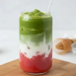 Strawberry matcha latte with pink strawberry layer and green matcha foam shown in an iced matcha latte aesthetic style.