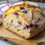 Lemon blueberry sourdough bread loaf with golden crust and visible blueberries sliced to show a soft flavorful crumb.