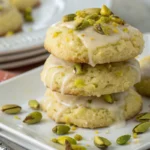 Lemon Pistachio Cookies stacked on a plate with visible chopped pistachios and light lemon glaze, showcasing soft bakery style cookies inspired by pistachio shortbread and Italian lemon cookie flavors.