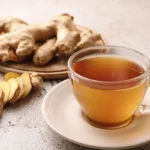 Ginger tea recipe made with fresh ginger root, served in a clear glass cup with sliced ginger on the side.