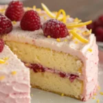 Lemon raspberry cake with fluffy layers and fresh raspberries, lightly frosted and garnished with lemon zest, showcasing a soft texture similar to chiffon cake and vibrant berry flavors