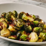 Brussels cabbage recipe served in a white oval dish with caramelized edges and crispy bits on a marble surface