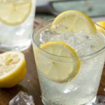 Coconut Water Lemonade served over ice in a clear glass with lemon slices, a refreshing coconut water electrolyte drink with a bright summer aesthetic.