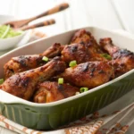 BBQ Chicken Drumsticks glazed with sticky barbecue sauce on a white plate with fresh herbs