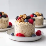 Loaded Overnight Oats with Flaxseed & Berries in a glass jar topped with fresh berries and almonds on a white table