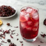 Hibiscus Iced Tea in a tall glass with lime slices and mint garnish on a bright table