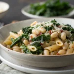 White Bean & Kale Pasta served in a wide bowl with grated Parmesan cheese and olive oil drizzle