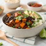 Black Bean & Sweet Potato Burrito Bowl with roasted sweet potatoes, black beans, rice, avocado, and fresh cilantro in a white bowl