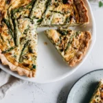 Asparagus & Leek Quiche golden baked with visible asparagus spears and melted cheese on a white plate