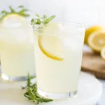 Classic Homemade Lemonade in a tall glass pitcher with fresh lemon slices and ice on a sunny table