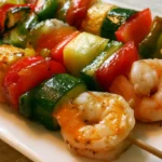 Shrimp kabobs with colorful grilled vegetables on a white platter garnished with fresh herbs