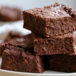 Sweet potato brownies stacked on a white plate showing fudgy texture with chocolate chips
