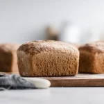 Rye bread sliced loaf on wooden board showing dense crumb texture with caraway seeds