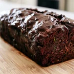 Chocolate zucchini bread sliced on a wooden board showing fudgy texture with chocolate chips