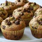 Chocolate chip zucchini muffins arranged on white plate with melted chocolate visible
