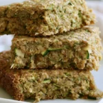 Zucchini bars with cream cheese frosting on a white plate with a fork