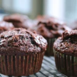 Chocolate zucchini muffins with chocolate chips on top arranged on a white plate