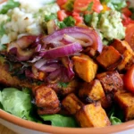 Sweet potato burger bowl with crispy roasted sweet potatoes, seasoned ground beef, fresh greens, and cherry tomatoes in a white bowl