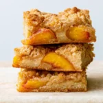 Peach pie bars cut into squares showing layers of buttery crust, sweet peach filling, and golden oat crumble topping