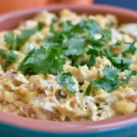 Street corn chicken casserole in a white baking dish with golden cheese topping and fresh cilantro garnish