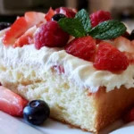 Tres leches cake slice on white plate showing moist layers soaked in three milks with whipped cream topping
