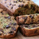 Chocolate chip zucchini bread sliced on a wooden board showing moist crumb and melted chocolate chips