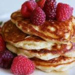 Pancakes from scratch stacked on a white plate with butter melting on top and maple syrup drizzling down the sides