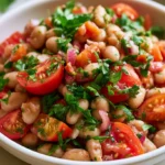 High protein bean salad with chickpeas, black beans, and kidney beans in a white bowl