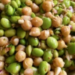 Chickpea edamame salad in a white bowl with bright green edamame, golden chickpeas, red tomatoes and fresh herbs