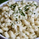 Pasta with philadelphia cream cheese served in a white bowl with fresh parsley garnish and grated parmesan