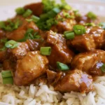 Bourbon chicken recipe with glossy caramelized sauce served over white rice with green onions
