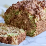 Snickerdoodle zucchini bread sliced on a wooden board showing moist interior and cinnamon sugar topping