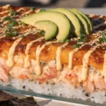 Sushi bake overhead view showing creamy golden topping over seasoned rice with nori sheets